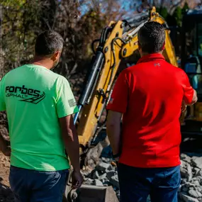 Two team members observing an excavation site, one wearing Forbes Asphalt gear