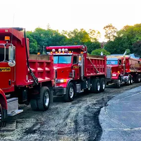 A line of red Forbes Asphalt dump trucks staged and ready for roadwork.