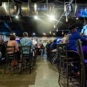 A bustling shot down the center of Brewbury’s dining and bar area shows packed tables, energetic guests, and an industrial-modern vibe with large brewing tanks and overhead lighting.