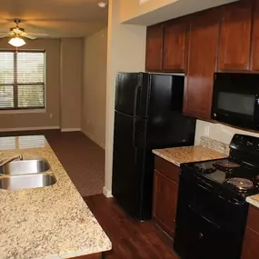 A kitchen with granite countertops and black appliances.