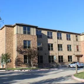 A large brick building with a parking lot in front at