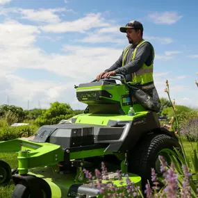 man riding lawnmower with flowers in the foreground