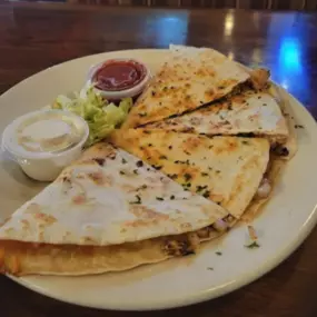 Our Chicken Quesadilla starts with our seasoned grilled chicken in a warm flour tortillas. Then we add cheddar jack cheese, onions and tomatoes. We serve it with salsa and sour cream. It's one of our most popular dishes on our menu. Hungry yet? There's no better place for lunch and dinner.