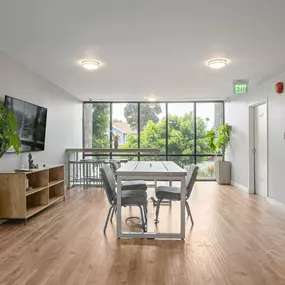 A room with a wooden floor and a large window with a view of trees.
