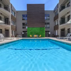 A swimming pool in front of a building with a green wall.