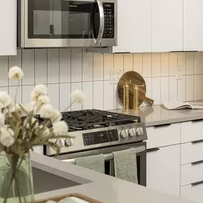 A modern kitchen with a gas stove, microwave, and white cabinets.