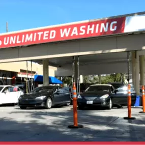 Red Carpet Car Wash Canoga Park location featuring drive-through lanes, Unlimited Wash Club signage, and multiple vehicles receiving full-service car wash and detailing.