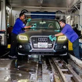 A Red Carpet team member performs a final hand-detailing on a vehicle exiting the tunnel wash. This close-up emphasizes the Canoga Park location’s attention to detail and premium finishing service—showcasing the difference of a full-service wash experience.