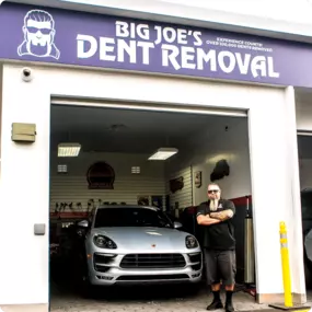Exterior view of Big Joe’s Dent Removal at Red Carpet Car Wash Manhattan Beach, featuring a technician and luxury vehicle in a professional dent repair bay.