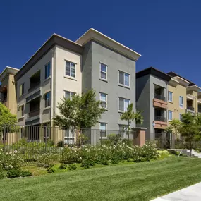 A row of modern apartment buildings with a well-maintained lawn in front.