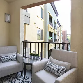 A balcony with two chairs and a table.