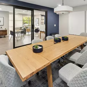 A conference room with a long table and grey chairs.