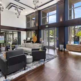 A large room with a lot of furniture and a view of trees outside the windows.