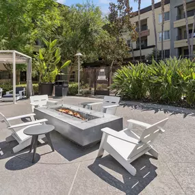 A white outdoor barbecue grill with chairs and a table is set up in a courtyard at The Kitt at Warner Center in Woodland Hills, CA, 91303