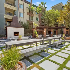 A patio with a table and chairs is surrounded by a grassy area and apartment buildings.