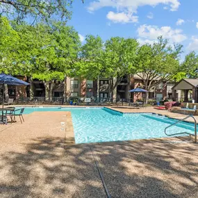 A swimming pool surrounded by trees and chairs. at Preston Bend, Dallas