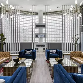 A lobby with blue couches and chairs and a large window