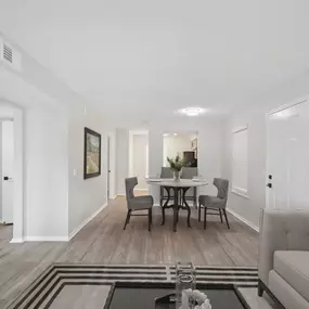 A living room and dining room with white walls and wood floors