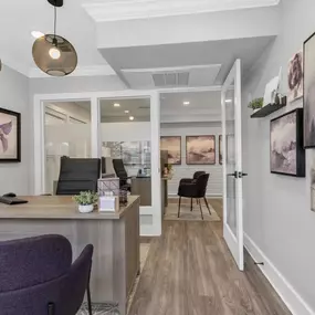 A home office with a desk and a hallway to a living room
