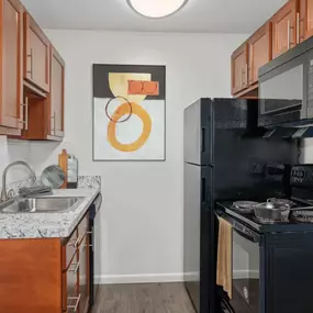 Kitchen with a black stove top oven next to a sink and a refrigerator