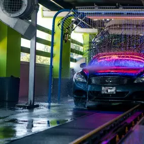 A stylish sedan rolls into Silverlake Speedwash’s express tunnel under vibrant LED lighting and multi‑stage foam—highlighting the advanced, tech‑forward wash experience and speedy 5‑minute turnaround.
