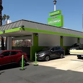 Vehicles entering the express tunnel at Speedwash Catalina. The site features a clean, modern bay with green accent roofing and a visible “Go Unlimited” $19.99/month promotional banner. Highlights efficient car wash service and traffic flow.