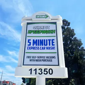 Bold roadside entrance sign for Olympic Speedwash in Los Angeles, highlighting their 5-minute express car wash and complimentary vacuum service with every wash—making speed and value their standout promise.