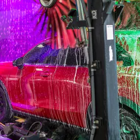 Inside the wash tunnel at Olympic Speedwash, showing a car enveloped in vibrant, multi-stage foam during the express wash cycle—demonstrating the attention to detail and visual appeal of their cleaning process.