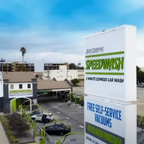 High-level aerial shot of the Northridge Speedwash at 9240 Reseda Blvd, highlighting the branded white tower signage, covered express wash bays, and free self-service vacuum area—positioned directly off the busy Reseda Blvd corridor in Northridge.