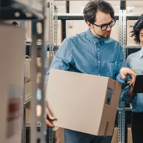 Two warehouse workers reviewing kitting options on a tablet.
