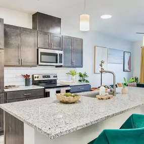 A kitchen with a granite countertop and green chairs