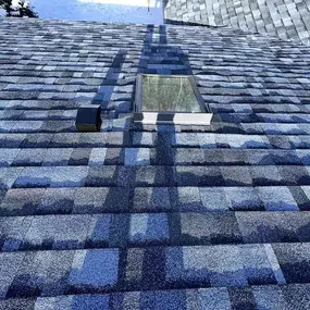 Completed roof replacement featuring architectural asphalt shingles and a new skylight installation.