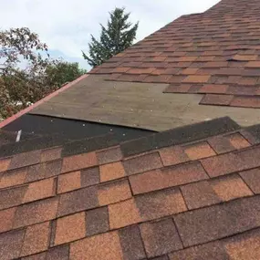 Roof repair in progress showing missing shingles and exposed decking.