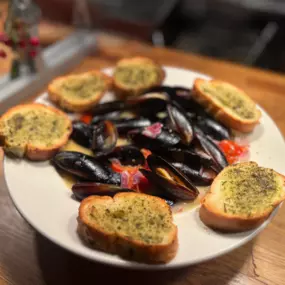 Mussels: Garlic, basil, white wine, lemon butter, anisette, tomatoes, onions, crostinis