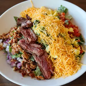 Romaine, assorted spring greens, bistro steak, hard-boiled egg, bacon, tomato, red onions, bleu cheese dressing & cheddar.