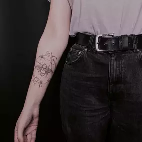 Filigranes Fineline Tattoo mit Biene am Unterarm.
