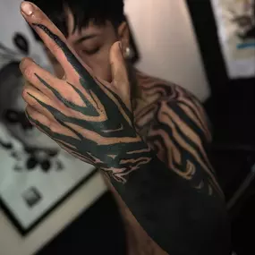 Blackwork Tattoo mit abstrakten Linien auf Hand und Arm.