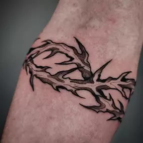Blackwork-Tattoo eines Dornenbands um den Arm.