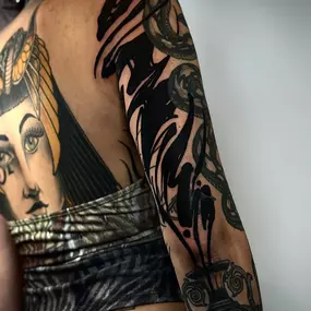 Blackwork Sleeve am Arm mit kräftigen schwarzen Flächen und abstrakten Mustern - eine Kombination aus organischen Formen und figurativen Elementen.