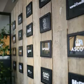 Framed client logos displayed on wooden feature wall at saintnicks office