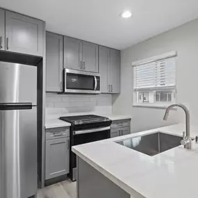 an empty kitchen with stainless steel appliances and white countertops