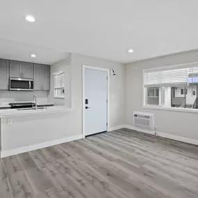 an empty kitchen and living room with a refrigerator and a sink