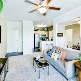 Interior living room with small brown coffee table, a side table, a beige couch and ceiling fan
