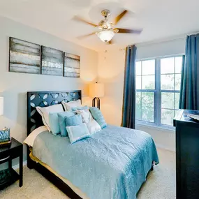 Interior bedroom with 2 large windows, black side table, black dresser, and celling fan