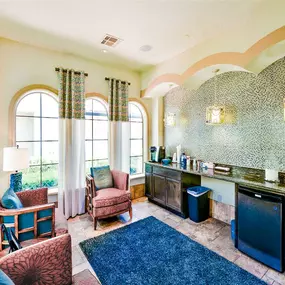 Clubhouse interior with mini fridge, refreshments, blue carpeting and red chairs