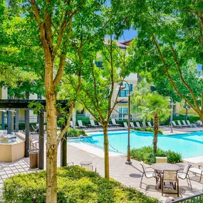 Sparkling pool surrounded by trees at Mission at La Villita Apartments in Irving, TX offers 1, 2 & 3 bedroom apartment homes with appliances.