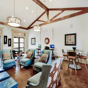 Community clubhouse with ample seating, soaring ceilings, hardwood floors, natural lighting and plenty of chairs and tables