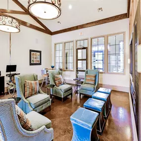 Interior of the community clubhouse, with a lounge area, blue chairs, and tall windows