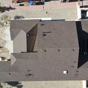 A high-angle, aerial shot showcasing a residential home with a complex, multi-pitched brown tile roof.
