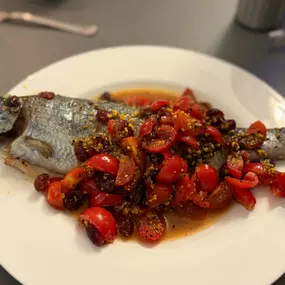Geschlossene Gesellschaft Ganzer Fisch mit Tomaten und Kräutern, kreativ zubereitet und präsentiert bei Geschlossene Gesellschaft Hamburg.
